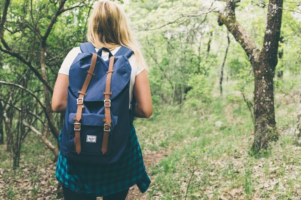 What to pack for a 3 hour hike in summer. A woman with her hiking bag on a forest trail.